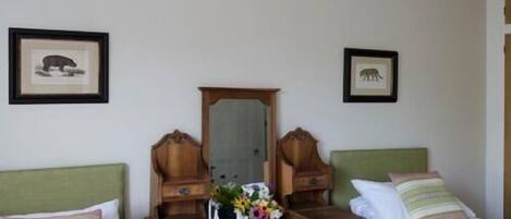 A room with two beds, a dresser with a mirror, and two framed animal pictures on the wall.