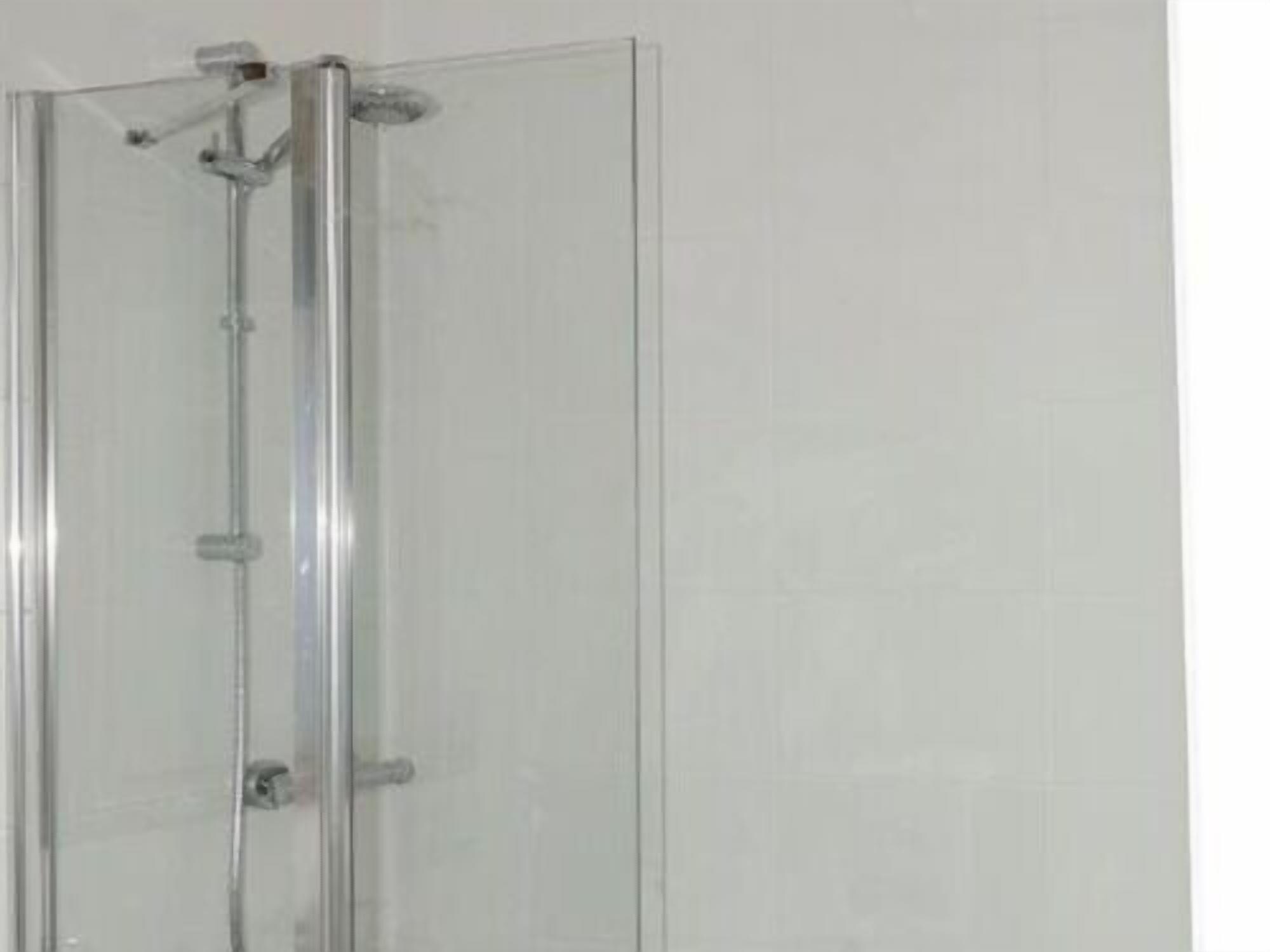 A glass-enclosed shower with a chrome frame and a control panel on the wall.