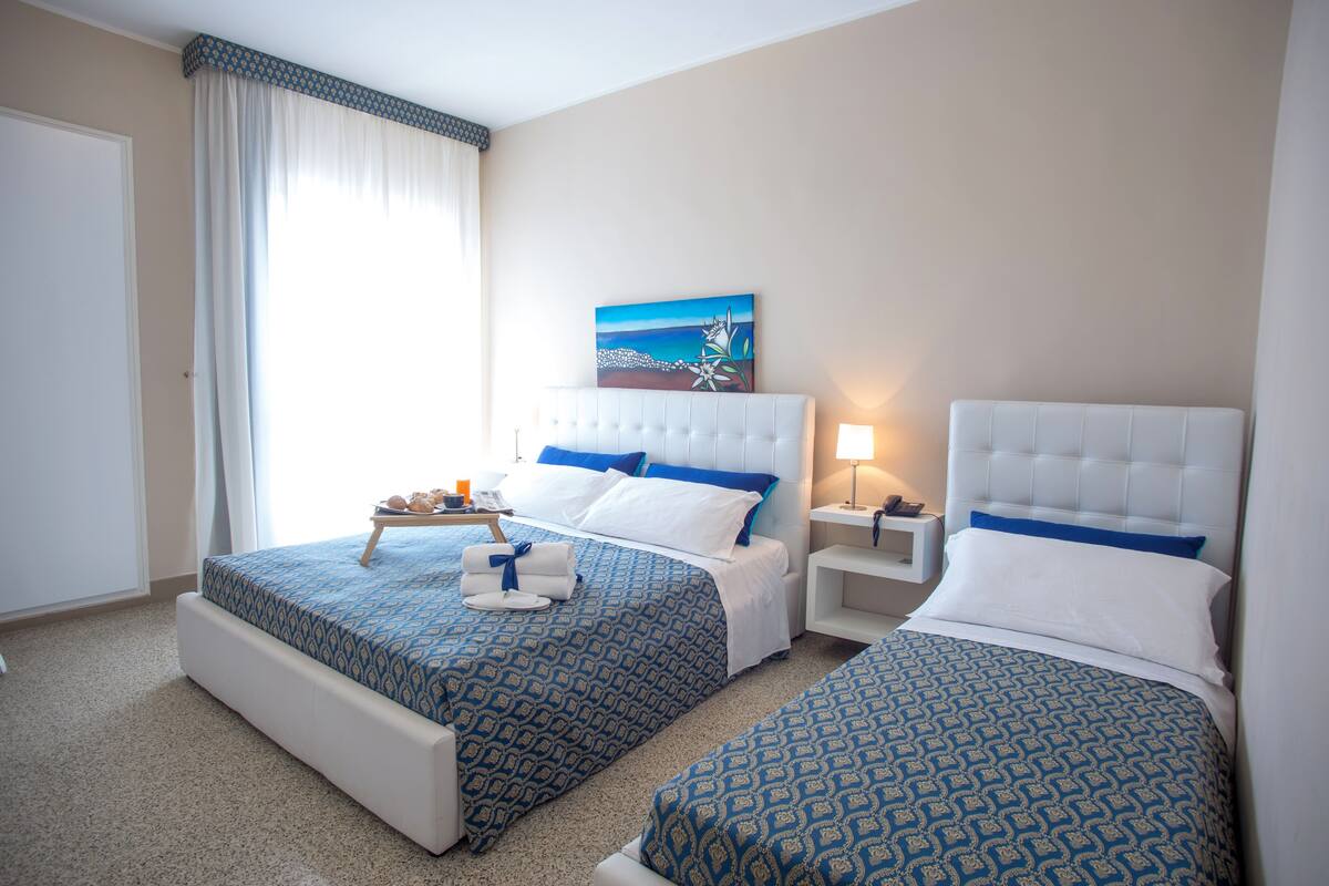 Habitació d'hotel amb dos llits, un quadre a la paret i una finestra amb cortines.