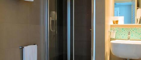 Uma casa de banho moderna com chuveiro em cabine de vidro, lavatório branco e sanita.