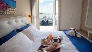 Ein Hotelzimmer mit Bett, Frühstückswagen und Meerblick.