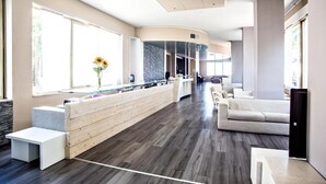 Eine moderne Hotelhalle mit Rezeption, Sitzgelegenheiten und großen Fenstern.