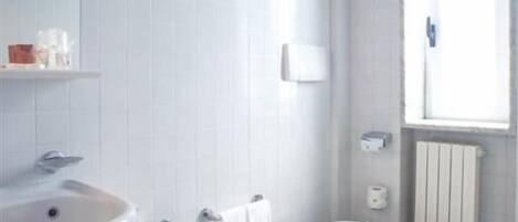 A modern bathroom with a sink, bidet, toilet, and a window providing natural light.