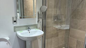 A bathroom with a white sink, a toilet, and a glass-enclosed shower area.