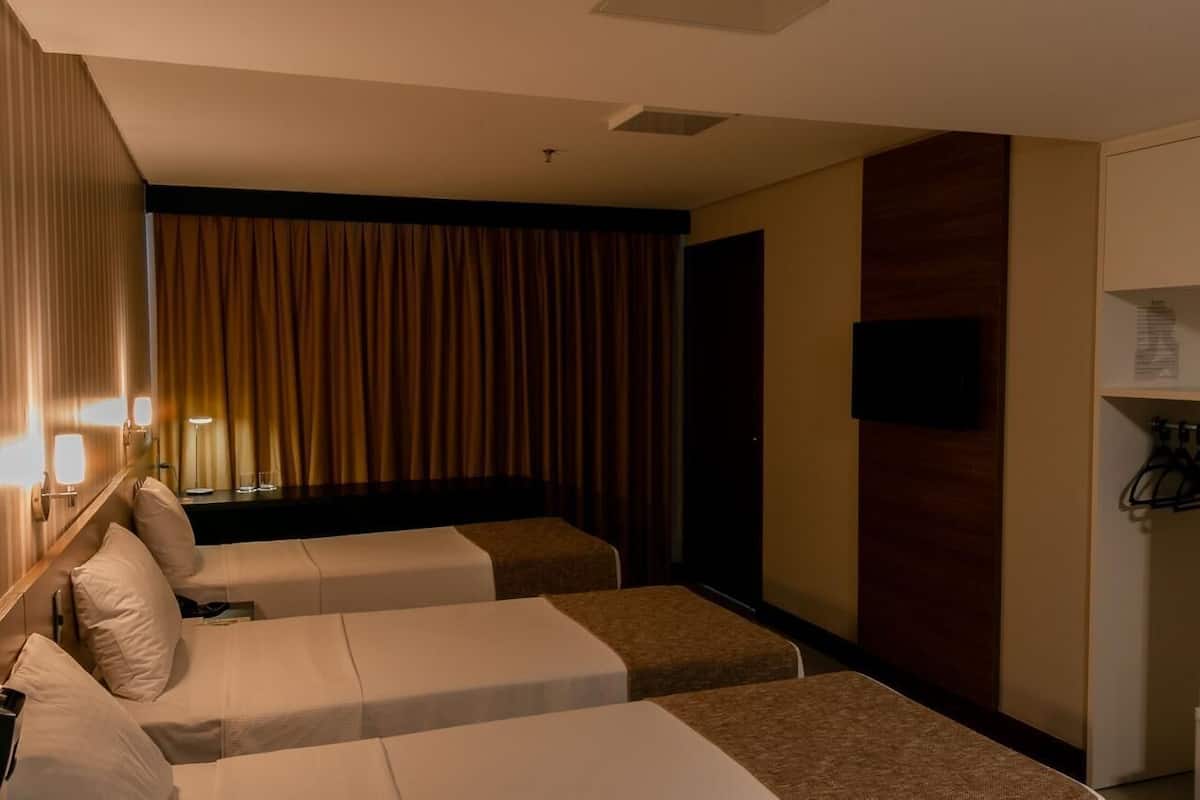 A hotel room with two beds, a TV, a desk, and a wardrobe.