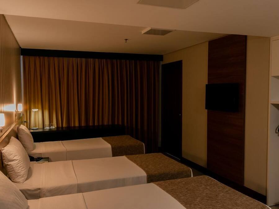 Habitación de hotel con dos camas, televisión, escritorio y armario.