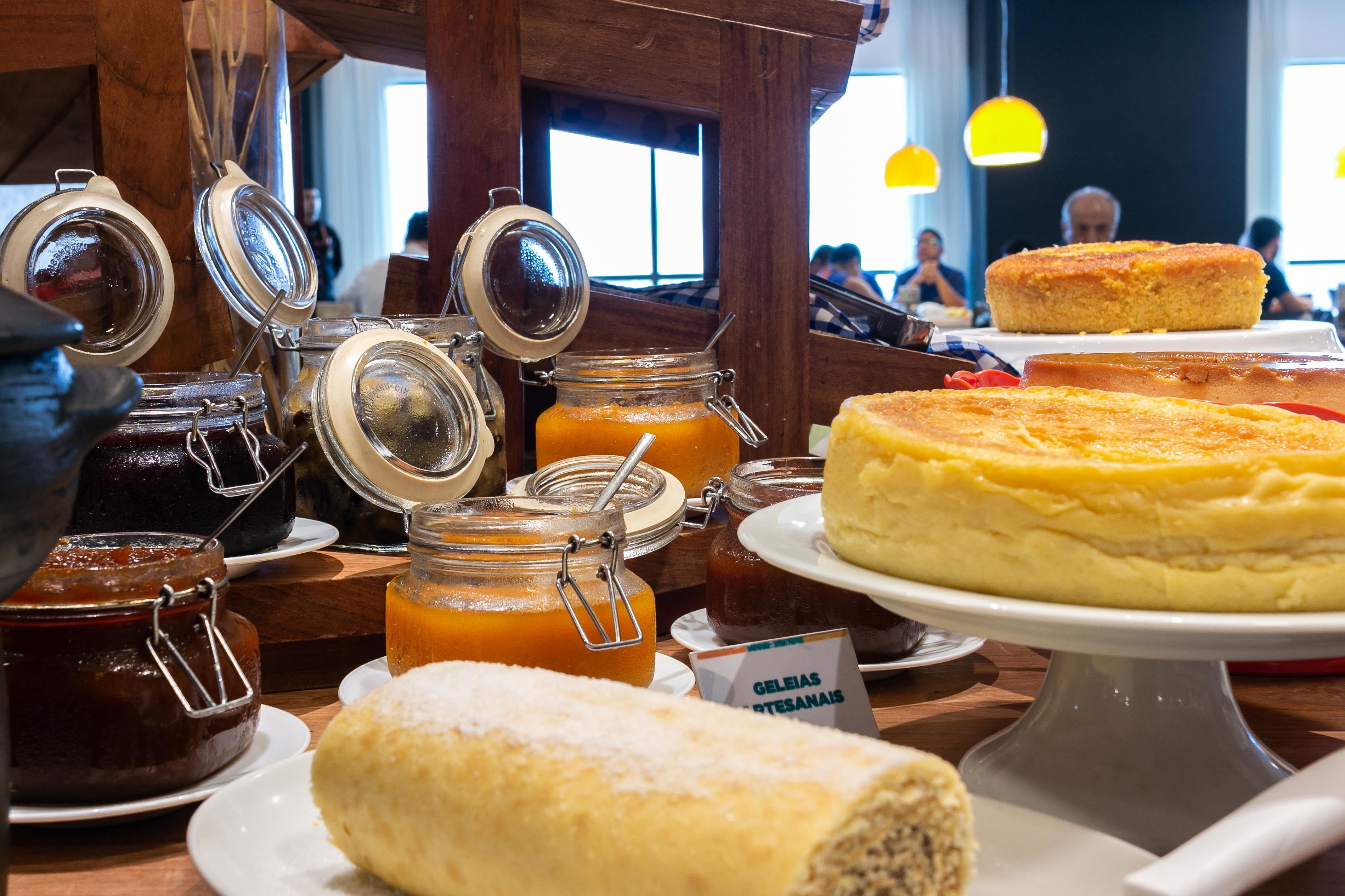 A variety of food items including jars of preserves and a large cheesecake on display.