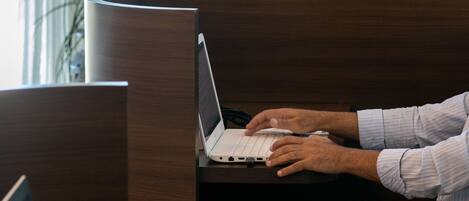 Une personne utilise un ordinateur portable sur un bureau en bois dans une pièce dotée d’une cloison incurvée.