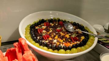 A bowl of fruit salad with a spoon, surrounded by watermelon slices.