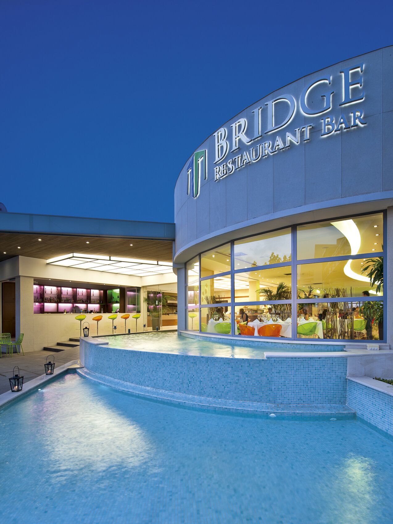 A modern restaurant with a pool area in front.