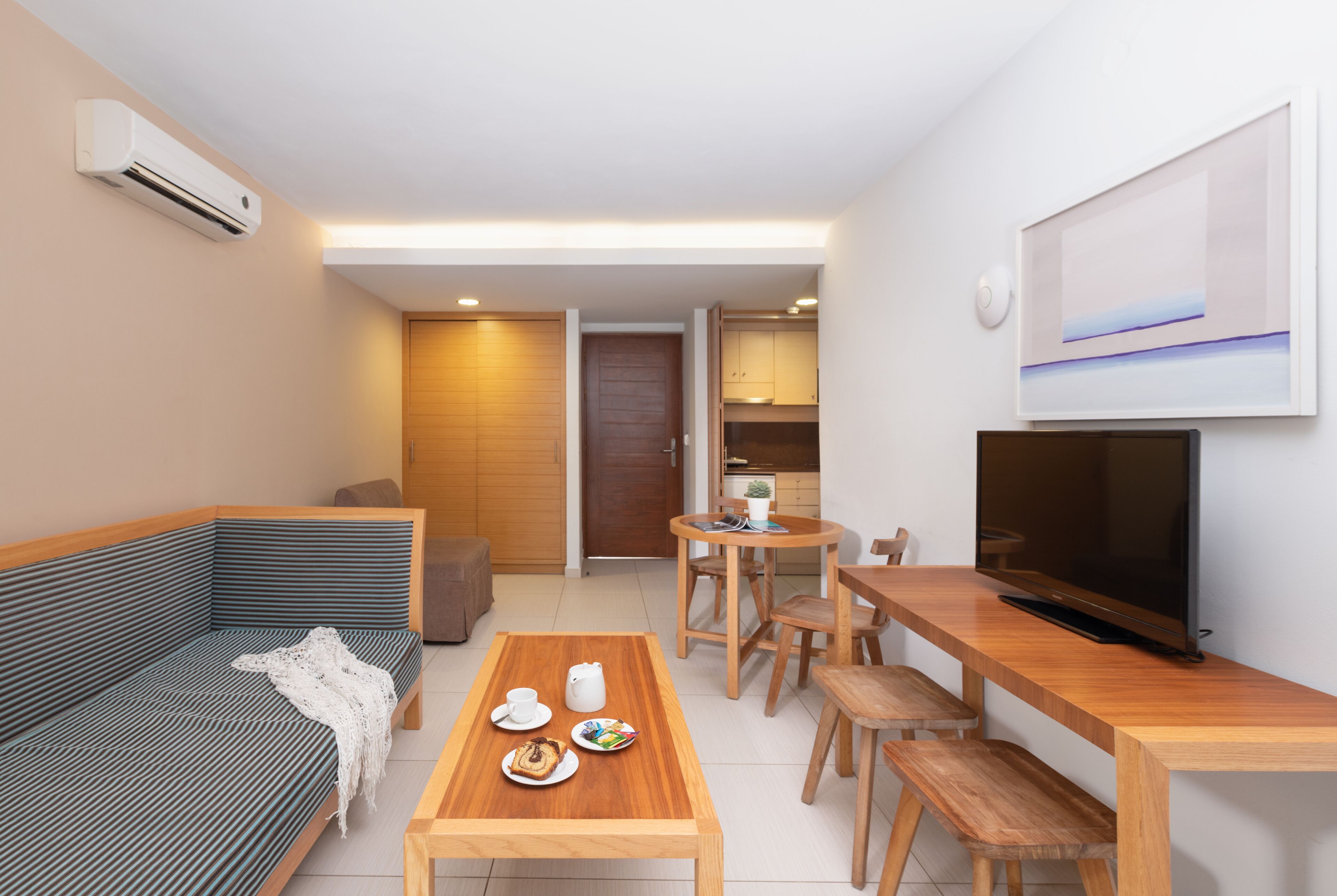 Una sala moderna con sofá, mesa de centro, televisor y comedor.