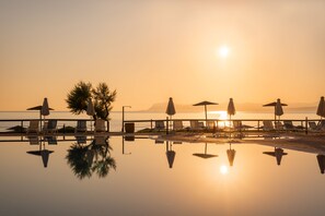 A serene poolside area with lounge chairs and umbrellas, reflecting the sunset over the water. - Iolida Beach by Smile Hotels (Chania)