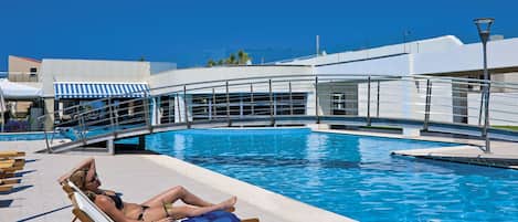 A pool area with lounge chairs and a glass bridge over the pool.