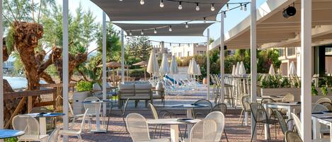An outdoor patio with tables and chairs, umbrellas, and a pool area.