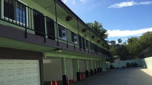 A building with a green facade, a covered parking area, and a row of orange traffic cones. - Eagle Rock Motel (Los Angeles)