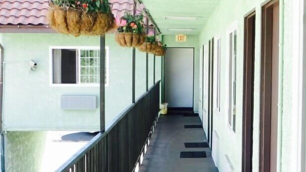 A corridor with a wooden railing, a trash bin, and a door marked "EXIT". - Eagle Rock Motel (Los Angeles)