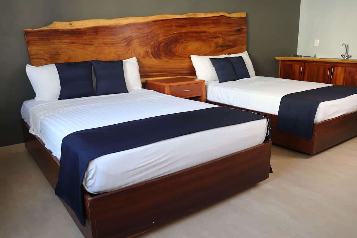 A hotel room with two beds, wooden headboards, and a wooden nightstand.