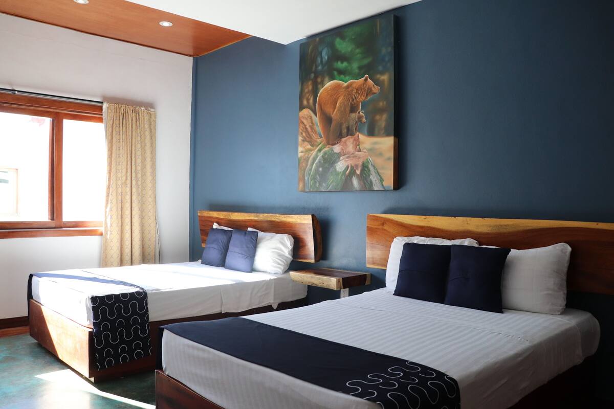 A hotel room with two beds, wooden headboards, and a large painting of a bear on the wall.