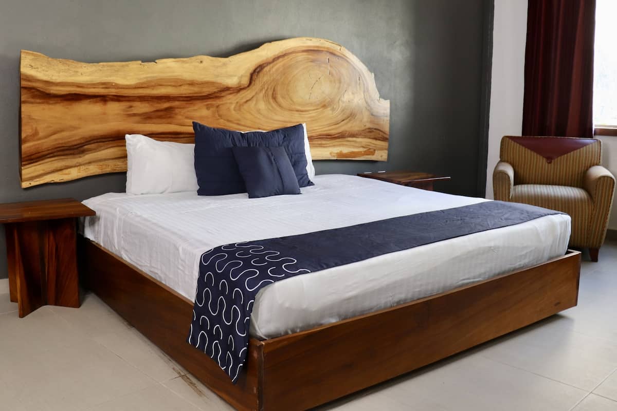 A large bed with a wooden headboard, white and dark blue bedding, and a patterned throw.