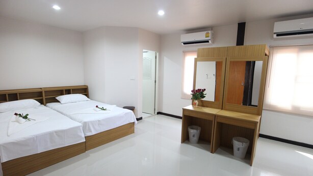 A hotel room with a double bed, a wooden headboard, a small desk with a mirror, a trash bin, and an air conditioning unit. - B Place Guesthouse (Ko Phi Phi)