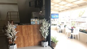 A reception area with a wooden counter, white chairs, and potted plants. - B Place Guesthouse (Ko Phi Phi)