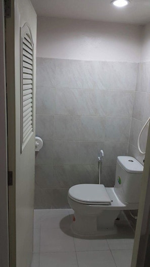 A small, compact bathroom with a toilet, a shower area, and a toilet paper holder. - B Place Guesthouse (Ko Phi Phi)