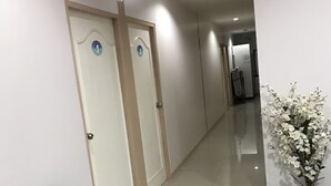 A hotel corridor with a seating area, a potted plant, and a door with a blue sign. - B Place Guesthouse (Ko Phi Phi)