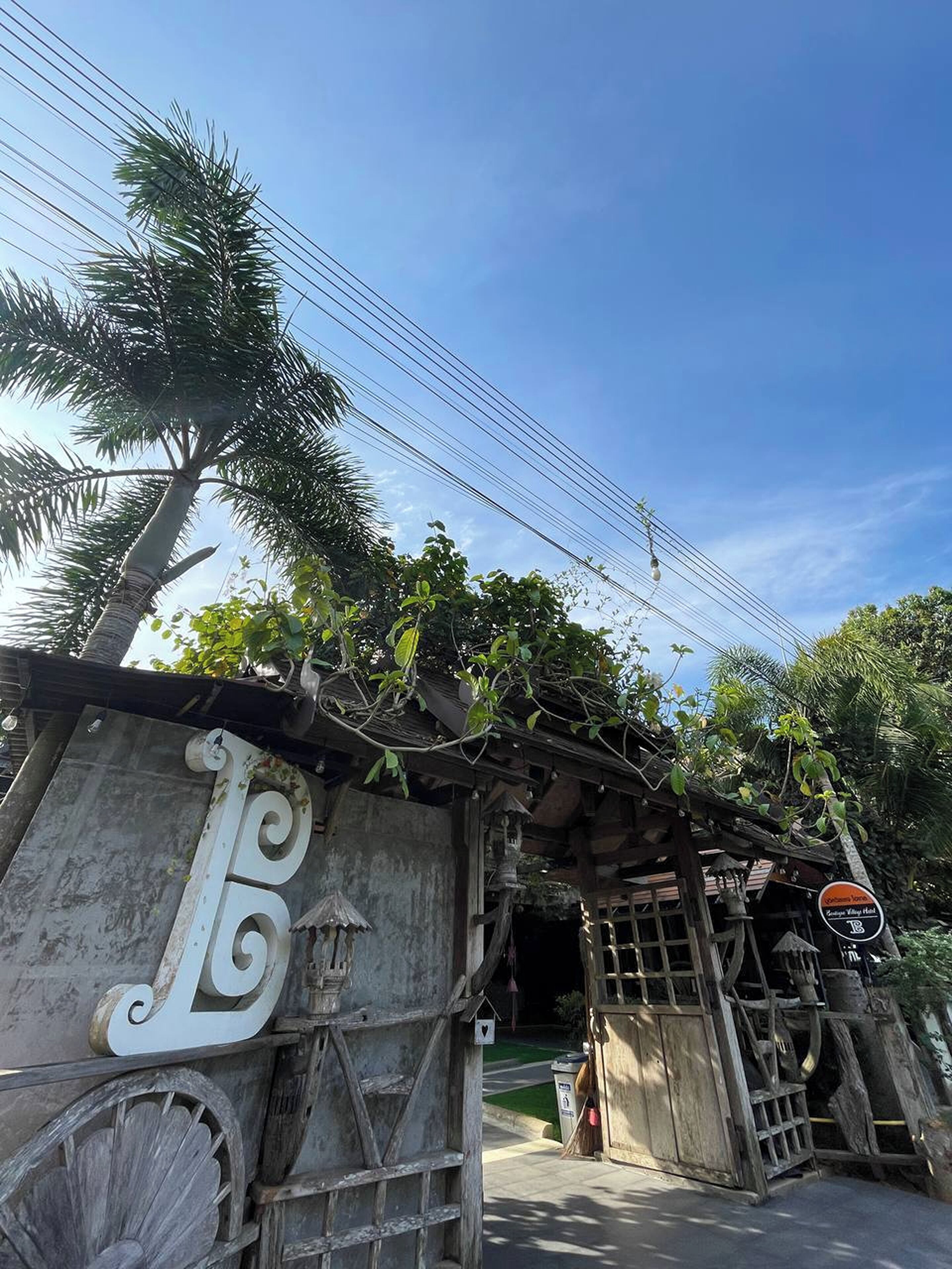 Un edificio rústico con un gran letrero en forma de 'L', una estructura de madera y un cartel que indica 'Zanzibar Village Hall'.