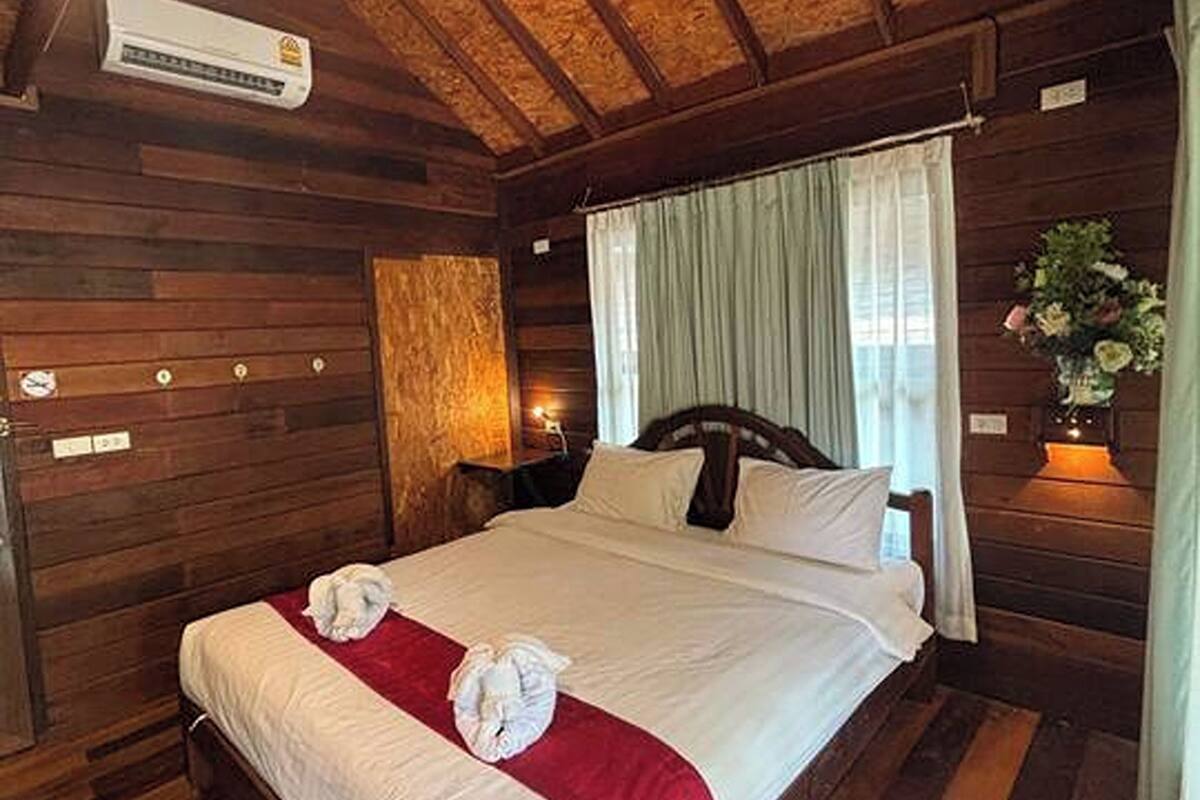 Ein Zimmer mit Holzwandverkleidung, einem großen Bett, einem Nachttisch und einer wandmontierten Klimaanlage.