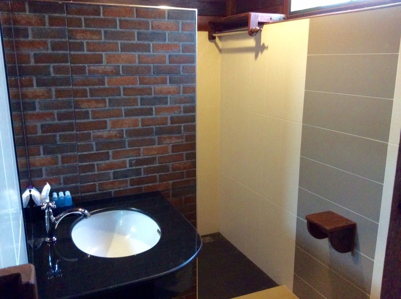 A bathroom with a black sink, a mirror, and a brick wall.