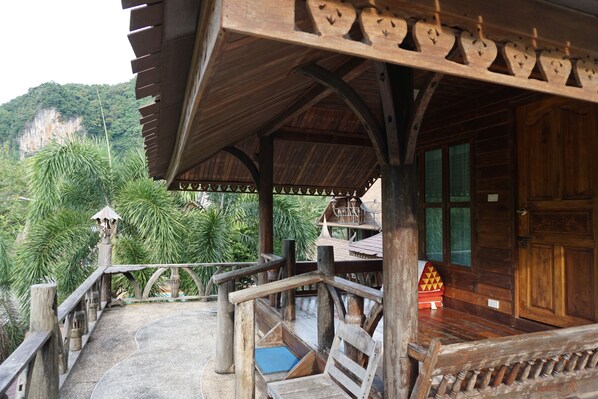 A wooden structure with a balcony overlooking a lush green landscape and a mountain.