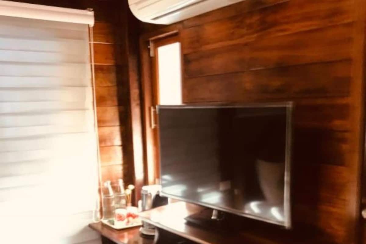 Una cocina compacta con refrigerador integrado, una pequeña encimera y un televisor de pared.