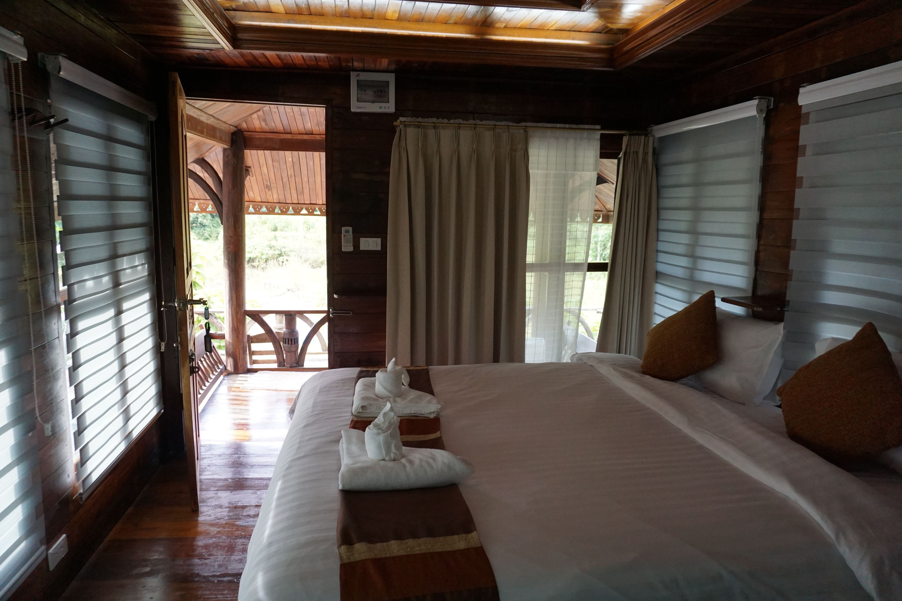 A well-appointed hotel room with a large bed, a wooden ceiling, and a view of the outdoors.
