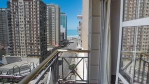 Un edificio alto con varios balcones que dan a una calle de la ciudad y al océano.