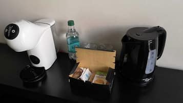 Una cafetera, una botella de agua y una caja de aperitivos sobre una mesa.