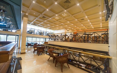 A spacious indoor area with a high ceiling, multiple seating arrangements, and a mezzanine level with a railing.