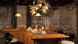 A wooden bar area with a stone wall backdrop, two pendant lights, and bar stools. - The Historic Webster House (Bay City)