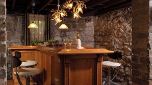 A rustic bar area with a wooden bar, two stools, and a hanging light fixture. - The Historic Webster House (Bay City)