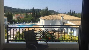 A balcony with a view of a swimming pool, a chair, and a railing. - San George (Corfu)