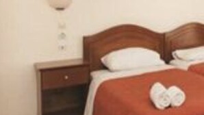 A hotel room with a wooden bed, white bedding, and a red accent pillow. - San George (Corfu)