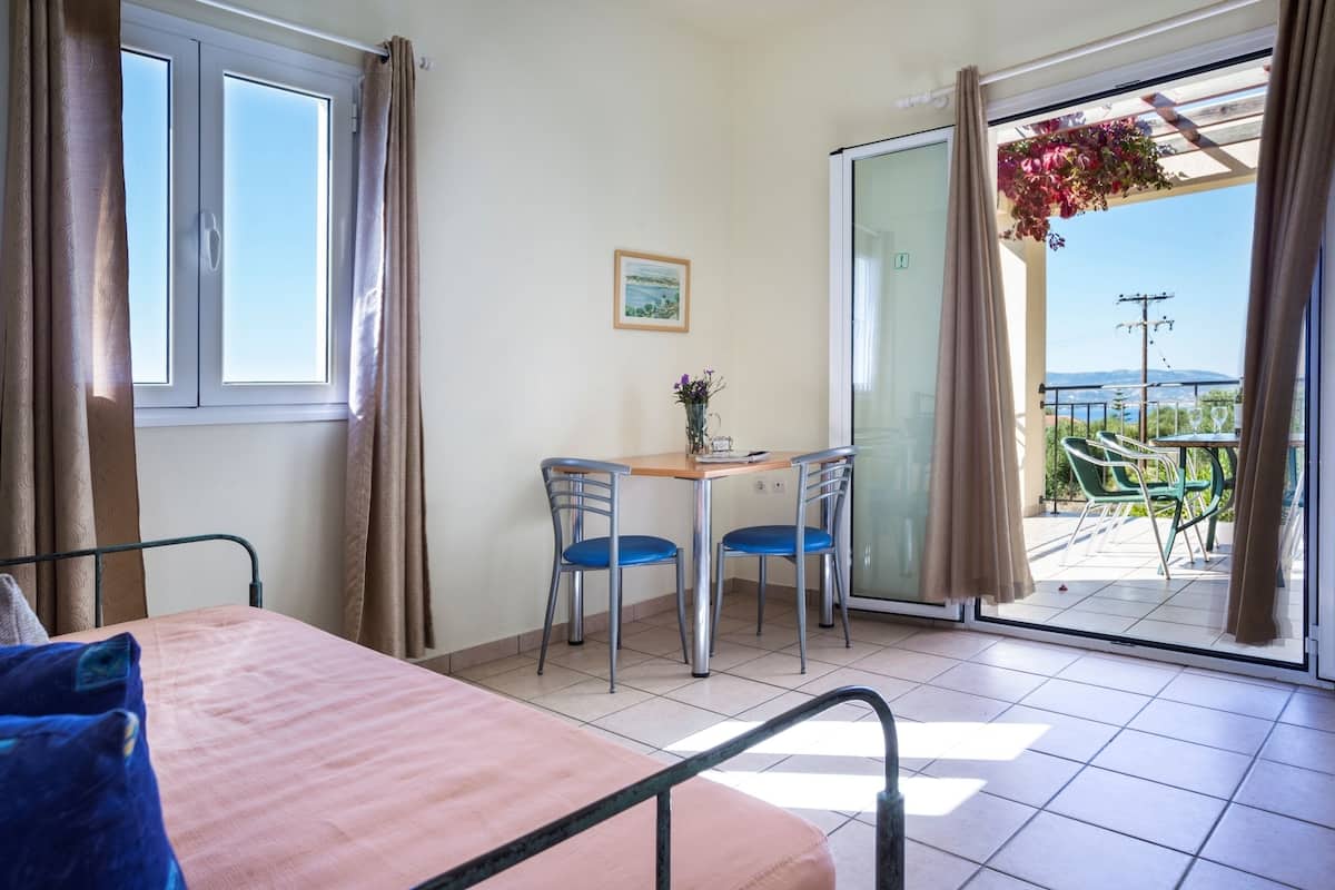 Una habitación con cama, una mesa con sillas, un ventanal y vistas al exterior.