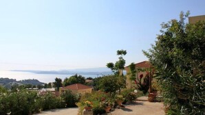 A coastal property with a paved driveway leading to a building with a red-tiled roof.