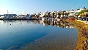 Una marina con barcos, una playa de arena y edificios al fondo.