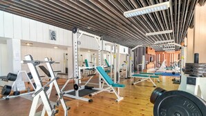 A gym with weightlifting equipment, benches, and a mirrored wall. - Amfora (Labin)