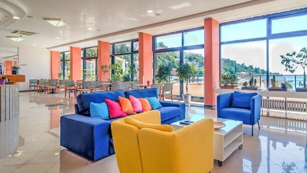 A spacious lobby with a blue sofa, yellow armchair, and a reception desk. - Amfora (Labin)