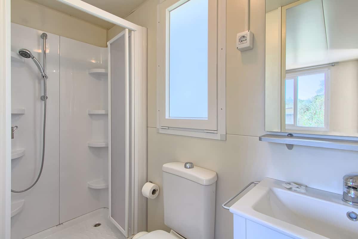 A bathroom with a shower, toilet, sink, and a window.