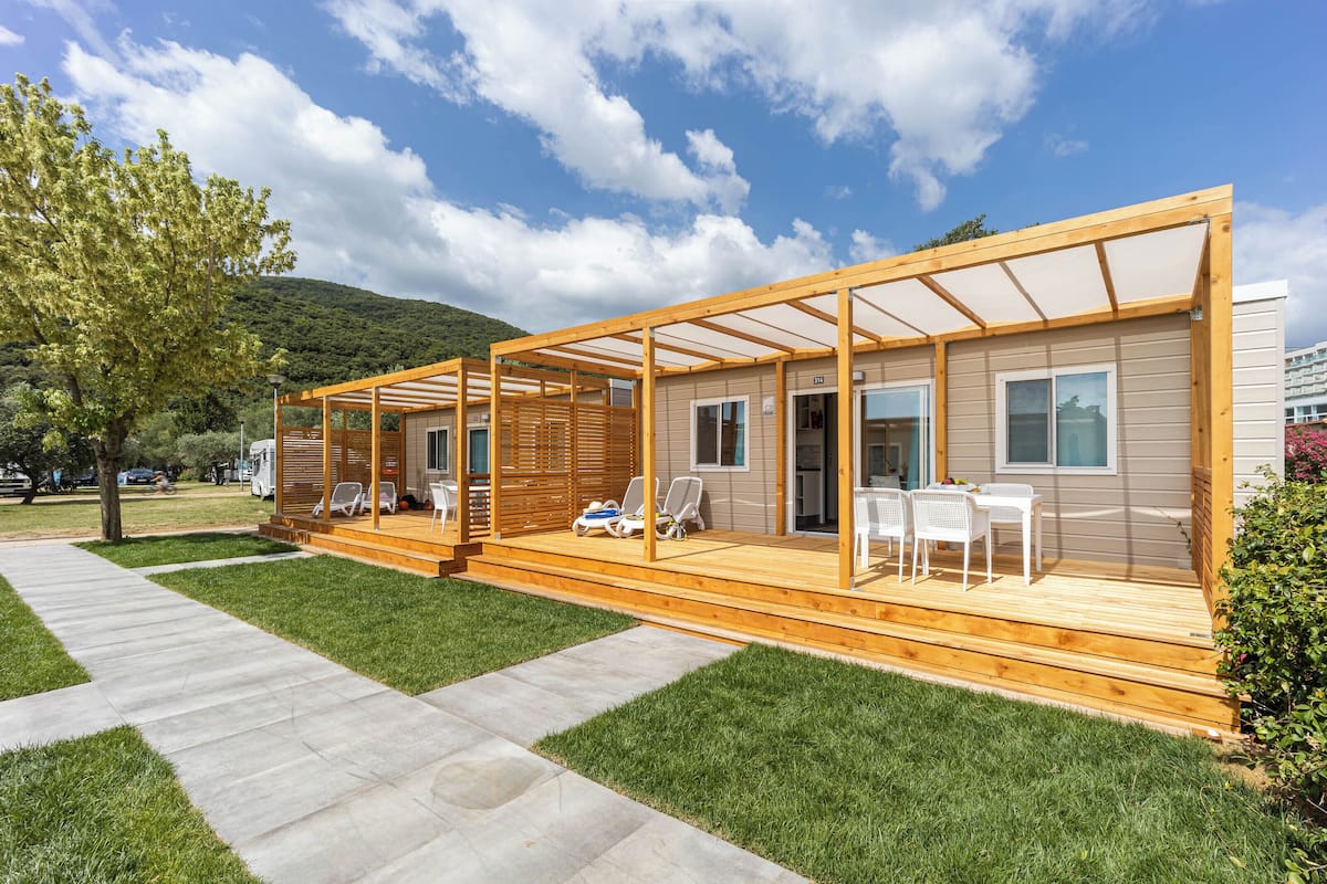 A modern, single-story cabin with a wooden deck and outdoor seating area.