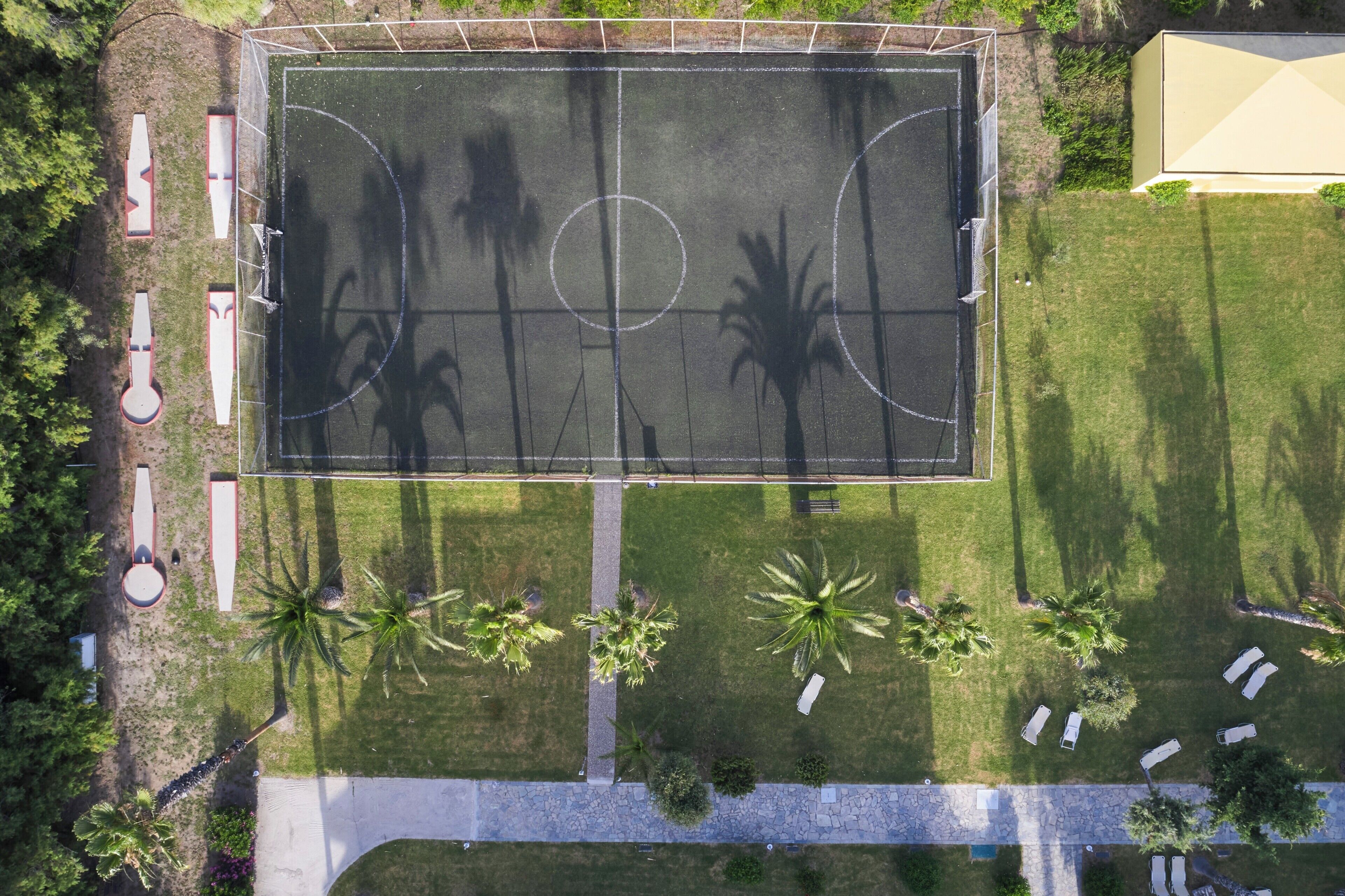 An aerial view of a sports court with surrounding greenery and seating areas.