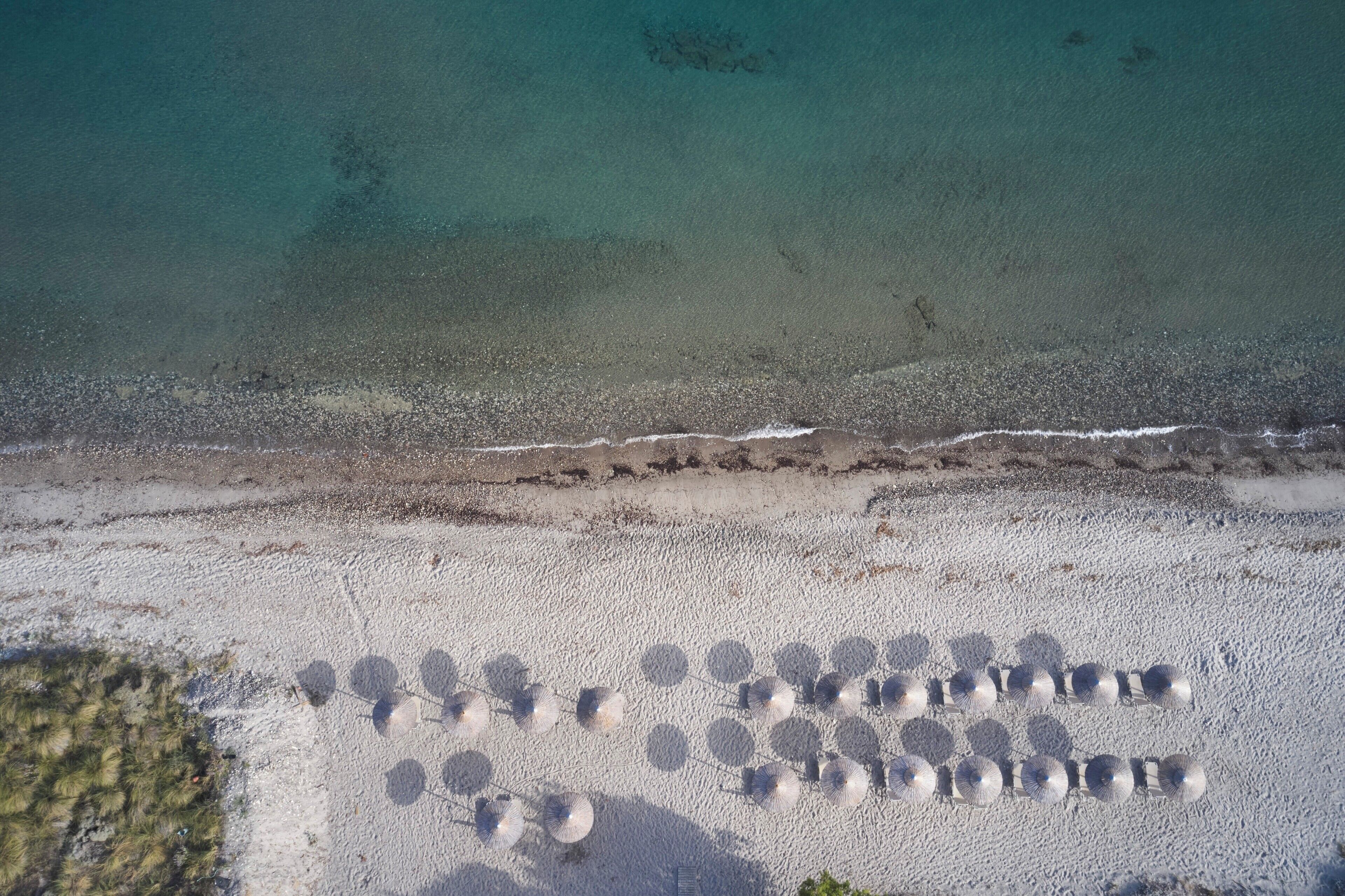 Vista aérea de una playa con una hilera de objetos esféricos alineados sobre la arena.