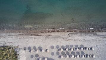 Vista aérea de una playa con una hilera de objetos esféricos alineados sobre la arena.